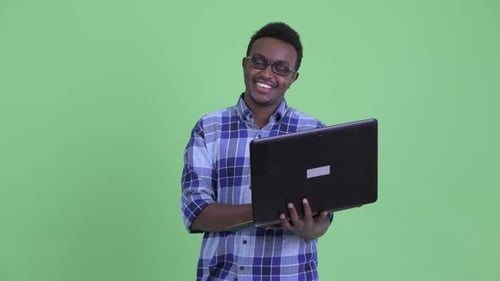 Young adult with laptop against green screen