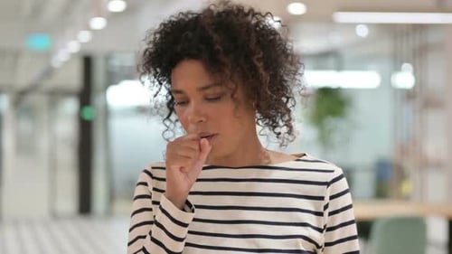 Woman Coughing Indoors in Office Setting