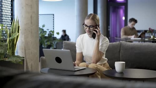 Woman Working on Laptop and Talking on Phone