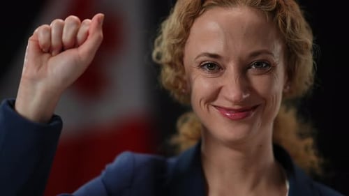 Smiling Woman Raises Fist in Front of Canadian Flag