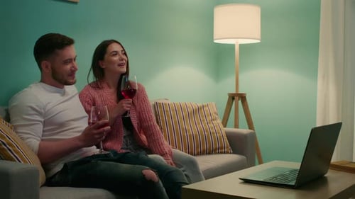 Couple Enjoying Wine Together at Home, Laptop in View