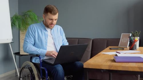 Man in Wheelchair Working on Laptop in Office