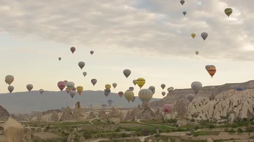 Hot-air balloons flying over the mountain landscape of Cappadocia, Turkey.