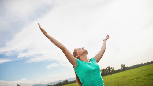 Woman with Arms Raised in Grassy Field