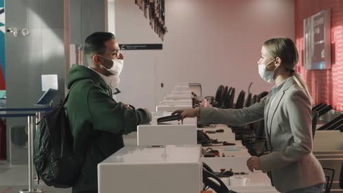 Airport Employee Checks Man's Documents, Both Wear Masks