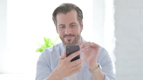 Man Cheers While Looking at Phone