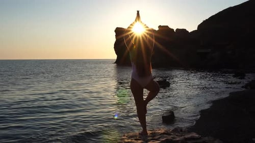 Young Woman with Long Hair in White Swimsuit Practicing Stretching Outdoors on Yoga Mat By the Sea