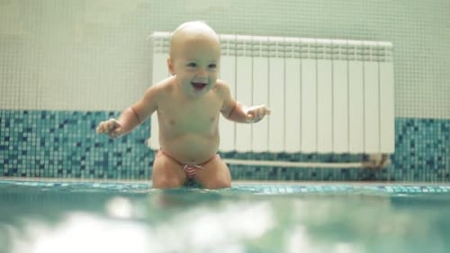 Happy Smiling Toddler is Jumping and Diving Under the Water in the Swimming Pool