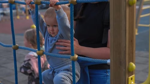 Mutter hält Sohn beim Versuch, auf Metallkonstruktion zu klettern