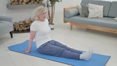 Senior Woman Sitting on Yoga Mat in Home