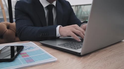 Suited Man Typing on Laptop at Desk