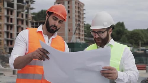 Engineers Reviewing Blueprints at Construction Site
