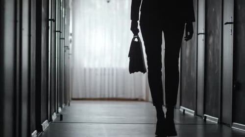 Silhouetted Figure Walking Down Dim Hallway