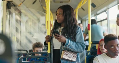 An Attractive Woman Rides in a Public Transport Bus Holding on to a Railing a