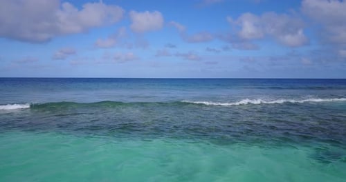 Wide fly over clean view of a white sandy paradise beach and aqua blue water background in high reso