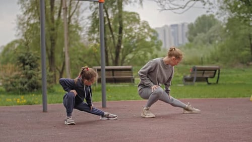 Slow Motion Mother and Daughter Doing Exercises on Open Air Sport Playground. Sportive Family