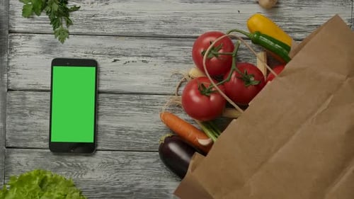 Groceries Spill on Table Next to Green Screen Phone