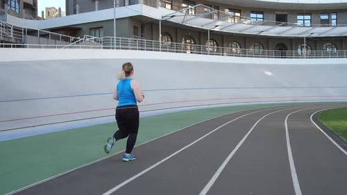Overweight Female Jogging on City Stadium Track