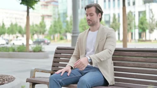 Man Sitting on Bench in Urban Park