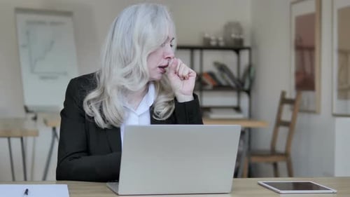 Senior Woman Coughing While Working on Laptop in Office