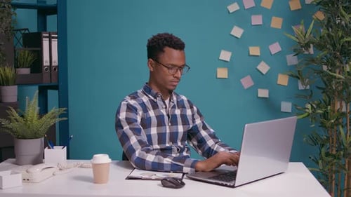 Young Adult Works on Laptop, Makes Roof Shape