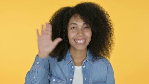 Afrikanische Frau winkt, gelber Hintergrund