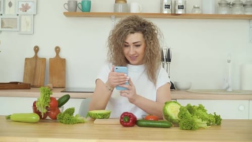 Woman with Curly Hair Using Phone in Kitchen