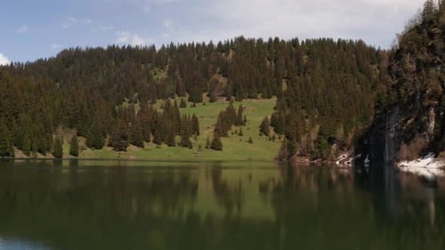 Flying low over beautiful lake in stunning area with mountains and trees