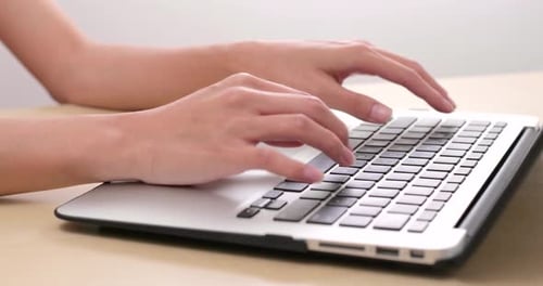 Hands Typing on Laptop Keyboard at Desk