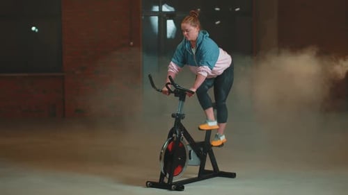 Healthy Caucasian Woman Exercising Workout on Stationary Cycling Machine Bike in Gym Slow Motion
