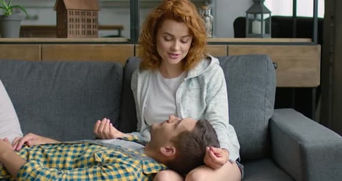 Young Couple in Love Is Lying on Sofa at Home, Enjoying Their Relationships