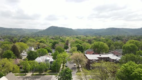 Blick die Wohnstraße in einer Stadt im Mittleren Westen hinunter auf baumbewachsene Berge in der Ferne.
