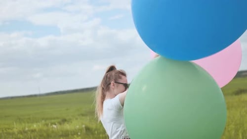Happy Girl with Big Multicolored Balloons Posing on the Field