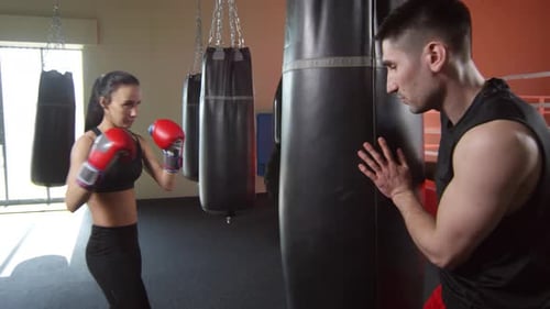 Woman Training with Coach, Punching Heavy Bag