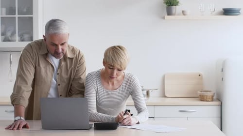 Man and Woman Working at a Laptop in Kitchen