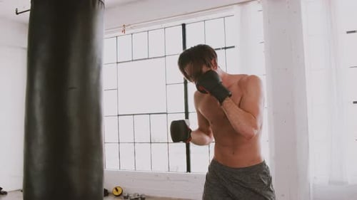 Shirtless Man Punching a Punching Bag