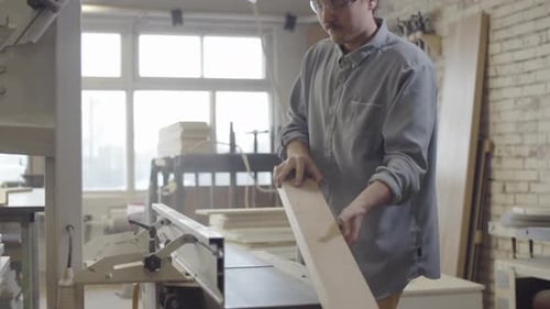 Young Carpenter Smoothing Surface of Wood Board on Jointer at Workshop