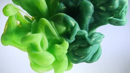 Green color paint drops in water against white background