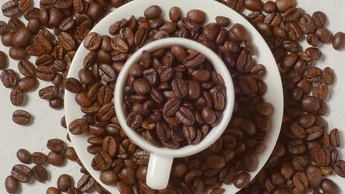 Top View Coffee Cup Filled with Coffee Beans. Coffee Beans Are Varied Nicely Textured Table