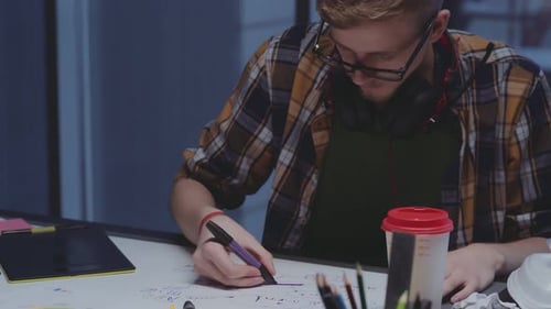 Diseñador creativo con auriculares hace bocetos, proceso creativo