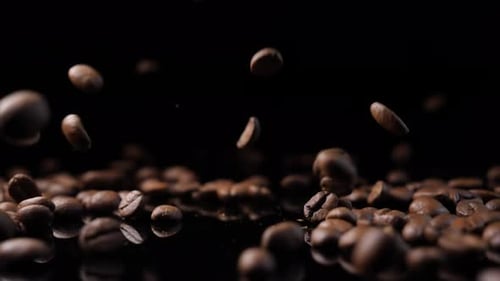 Roasted Coffee Beans Falling on Dark Surface