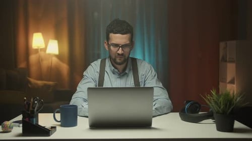 Smiling Businessman Working on Laptop Computer at Home Office
