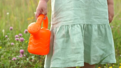 Young Child Holding Watering Can in a Meadow