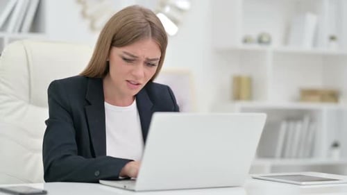 Worried Woman Types on Laptop in Office