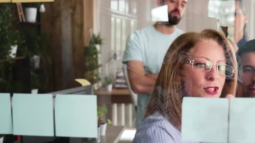 Diverse Team Collaborating with Sticky Notes on Glass