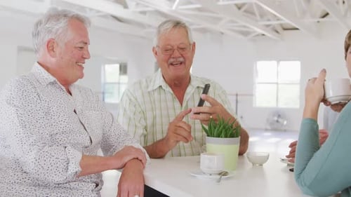 Senior Adults Laughing Over Mobile Phone At Table