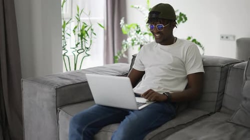 Black Man Works at a Laptop Makes Video Conferences or Video Call