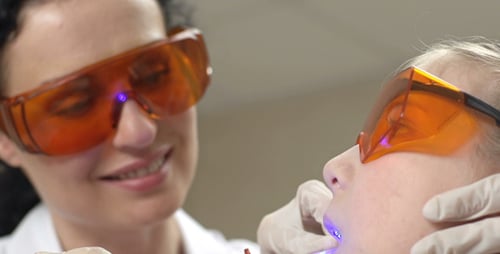 Dentist Curing Patient's Teeth with Blue Light