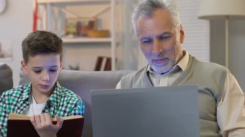 Grandfather and Grandson Reading Book, Using Laptop