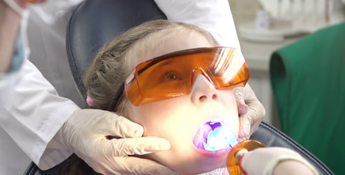 Dentist Examining Child's Teeth With Dental Light